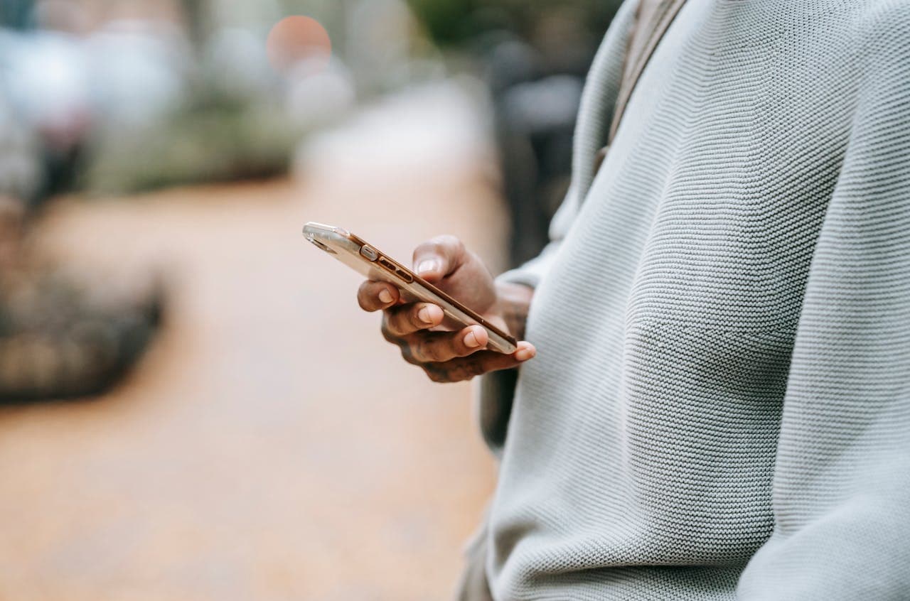 person receiving phishing scam text message on their phone while outside